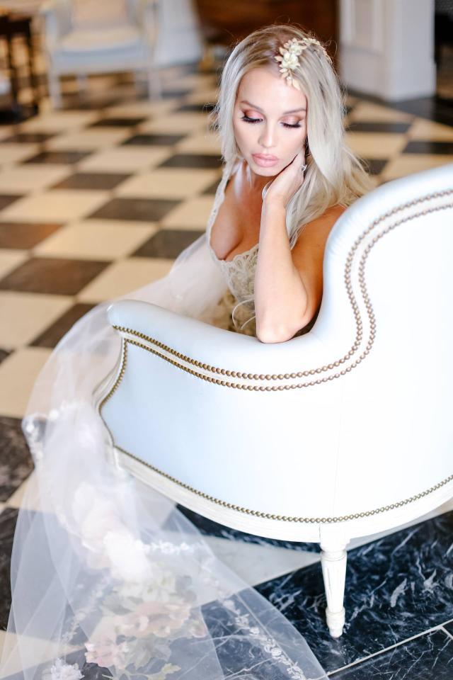 Bride Sitting on White Chair Looking Over Shoulder at Rhiannon & Joshua's Wedding