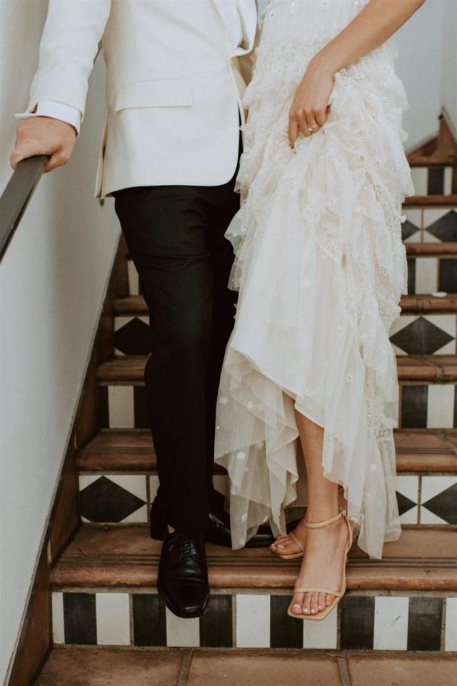Bride and groom on stairs shown from torso down for Paulina & Cam’s Wedding