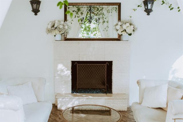 View of couches in front of fire place with mirror and flowers for Paulina & Cam’s Wedding