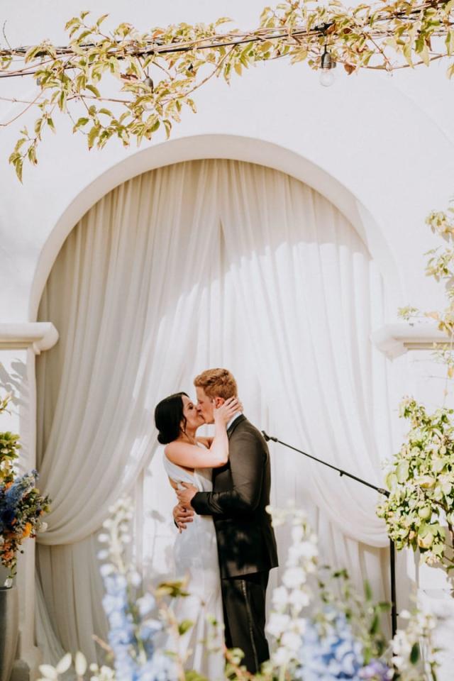 Brdie and groom kissing under archway for Veronica & Jake’s Wedding