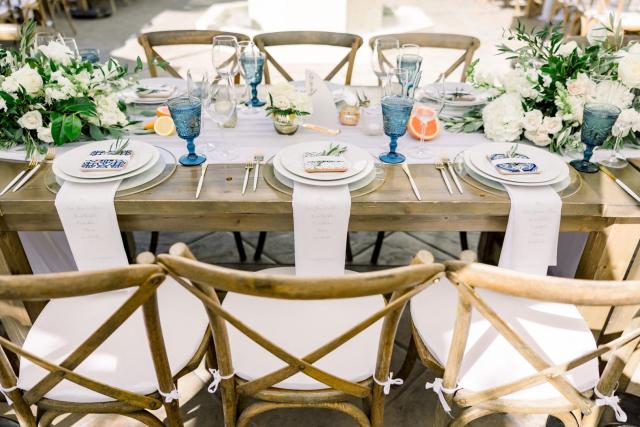 Table of 6 showing table sets, menu, blue glasses, candles, cut orange/lemon, and flowers for Sara & James’ Wedding