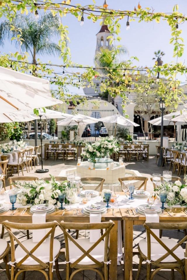 Cross wise view of courtyard wedding tables with creepers and andn umbrellas overhead for Sara & James’ Wedding