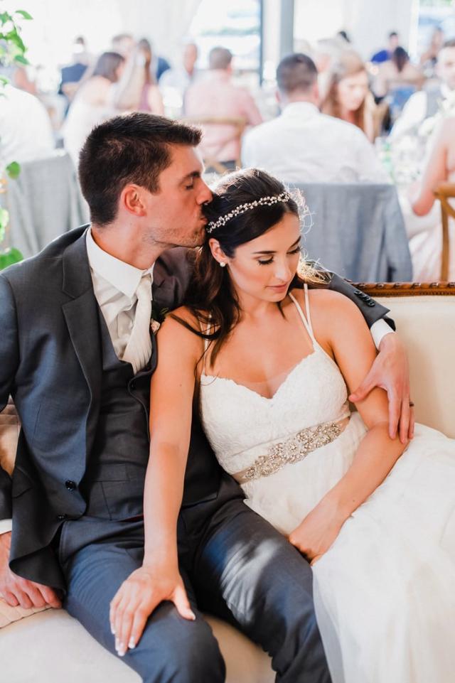 Groom kisses the bride's head as they sit comfortably for Jennifer & Lars' Wedding
