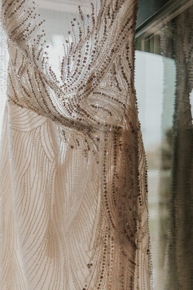 Wedding dress hanging up, with the sun shining through for Ivanka & Victoria's Wedding