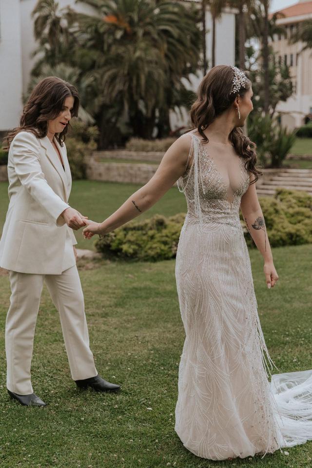 Bride and groom hold hands, looking into the distance at Ivanka & Victoria's wedding