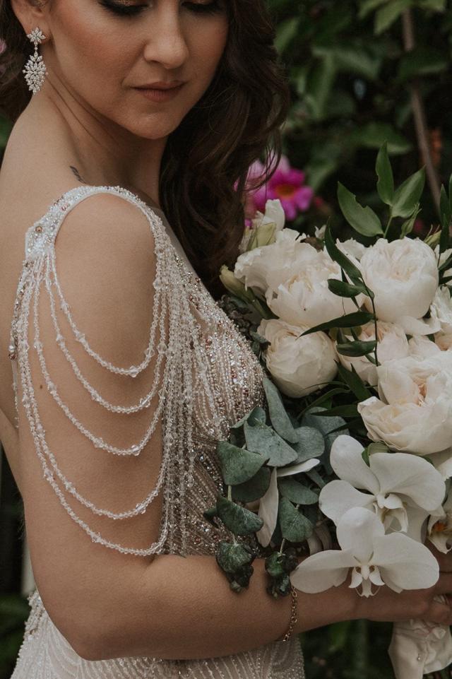 The bride looks over her shoulder, holding flowers for Ivanka and Victoria's wedding.
