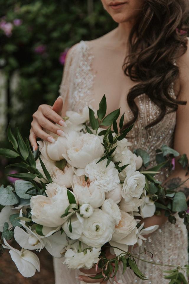 The bride looking down at the flowers, her hand caressing them, for Ivanka & Victoria's wedding.