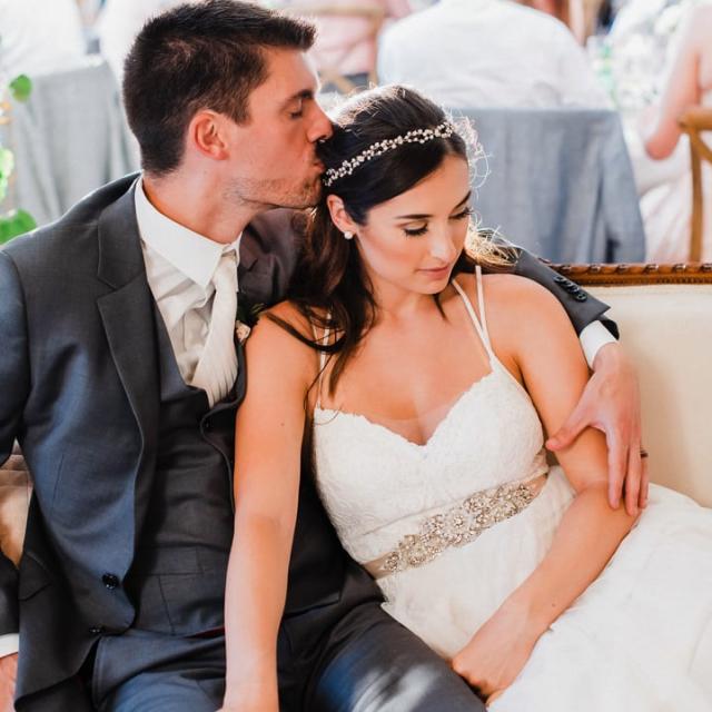 Groom kisses the bride's head as they sit comfortably for Jennifer & Lars' Wedding