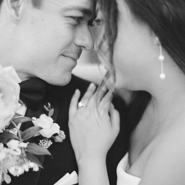 A bride and groom touch foreheads and smile softly during their wedding.